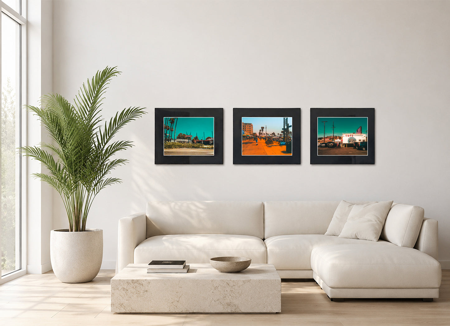 Three framed fine art photography prints displayed as a triptych gallery wall above a sofa with plant.