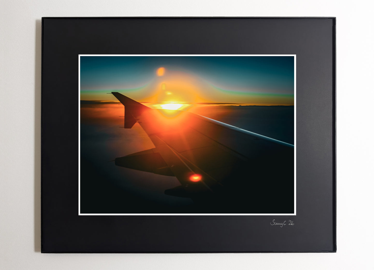Framed artwork of an airplane wing with sunset in the background on a blue sky
