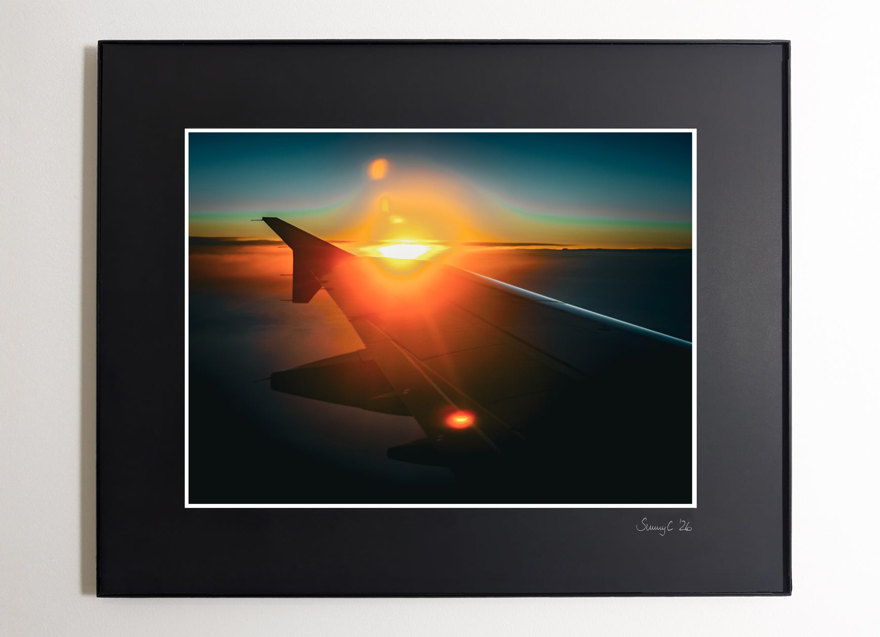 Framed artwork of an airplane wing with sunset in the background on a blue sky