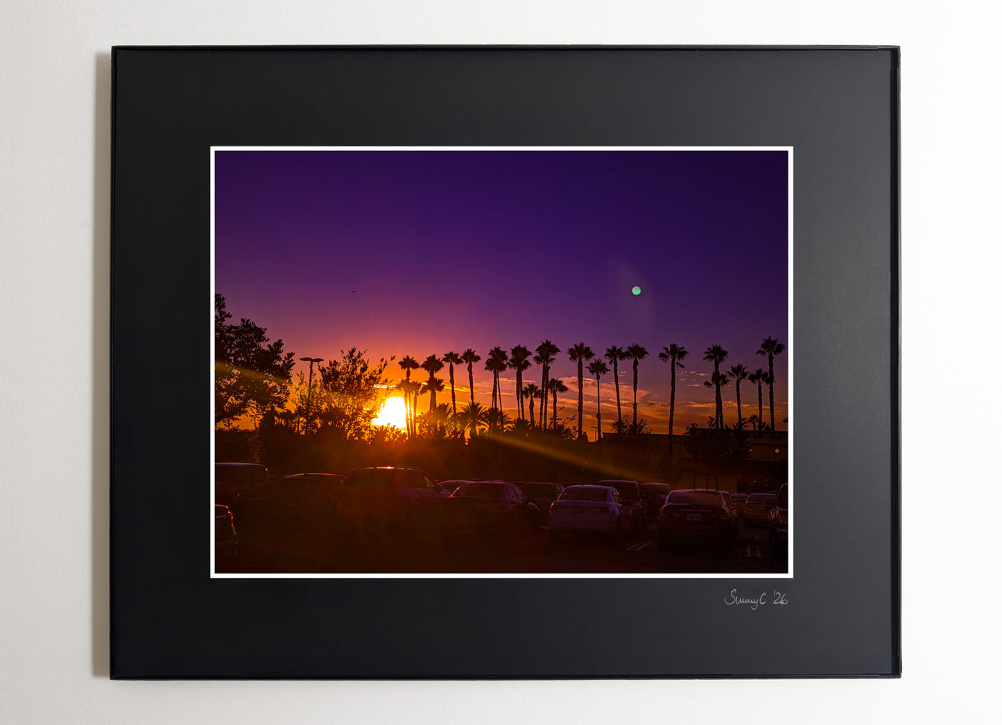 Framed photograph of a California sunset with palm trees, set against a purple sky