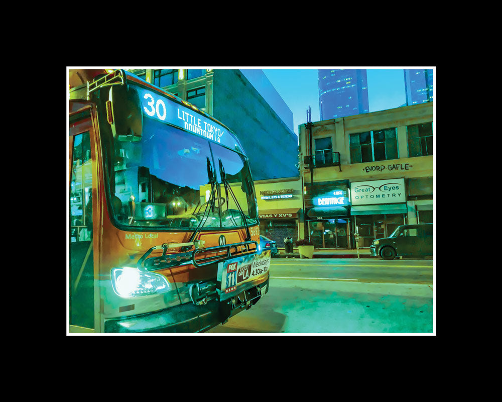 City bus in Downtown Los Angeles in direction to Little Tokyo passing between buildings on a quiet street