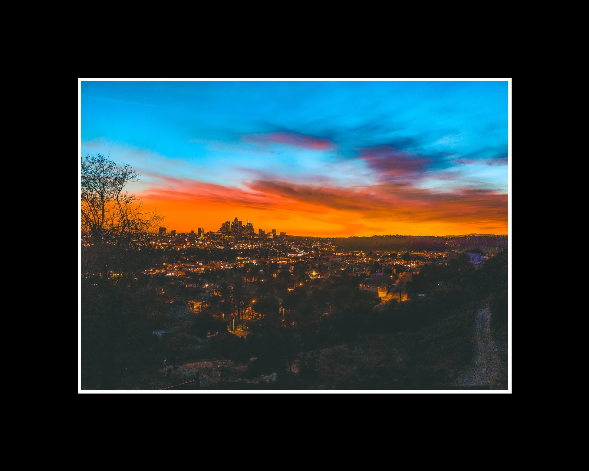 Rare view of DTLA skyline and Dodger Stadium at sunset in an orange mood and lit street lights