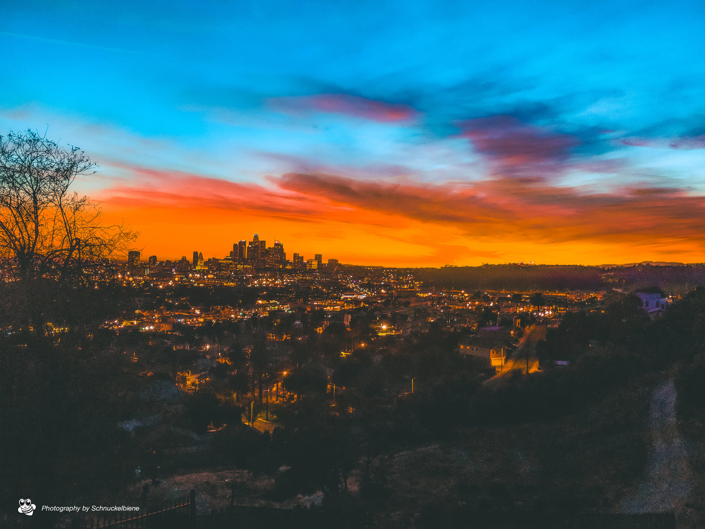 Rare view of DTLA skyline and Dodger Stadium at sunset in an orange mood and lit street lights