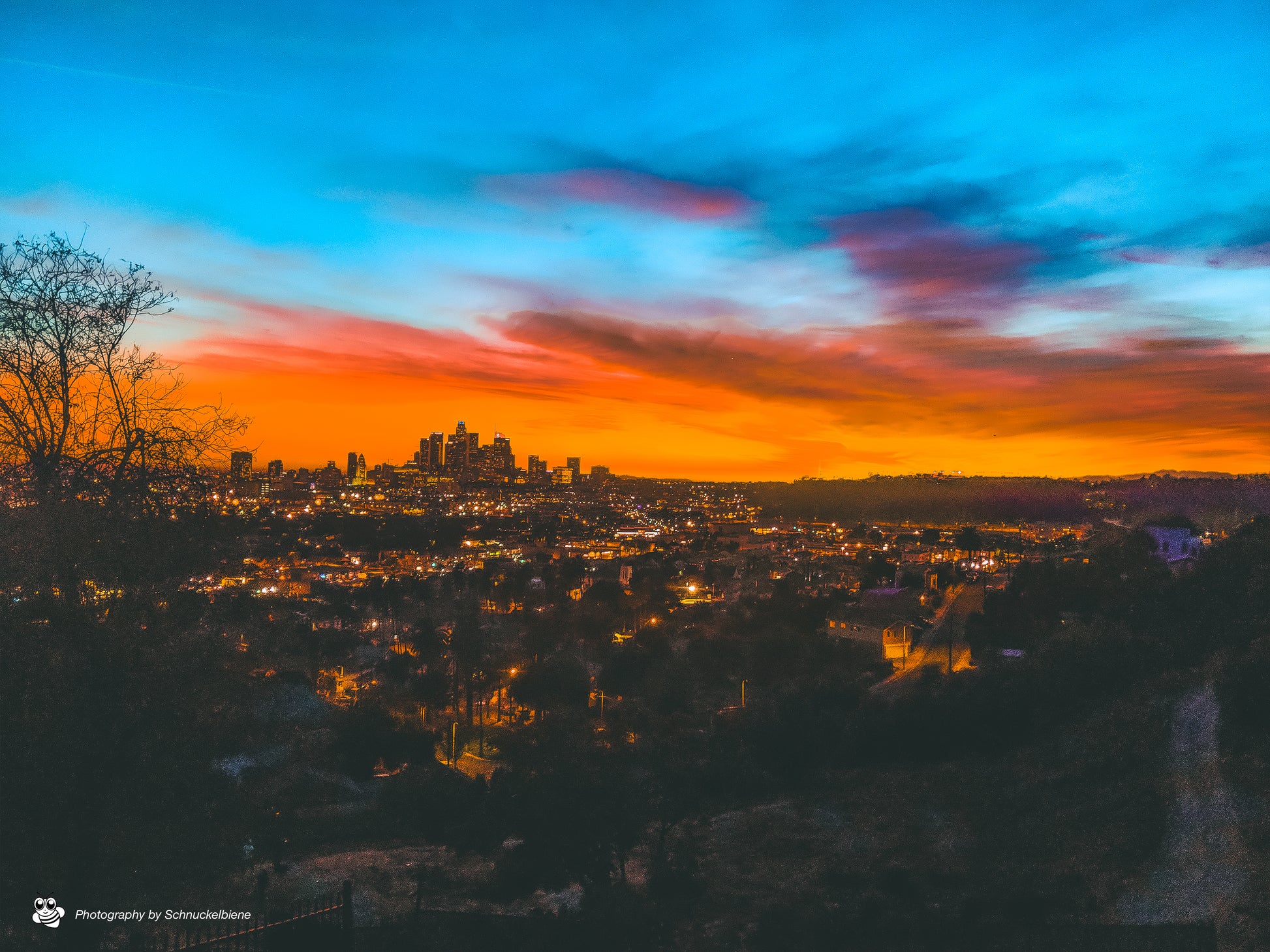 Rare view of DTLA skyline and Dodger Stadium at sunset in an orange mood and lit street lights