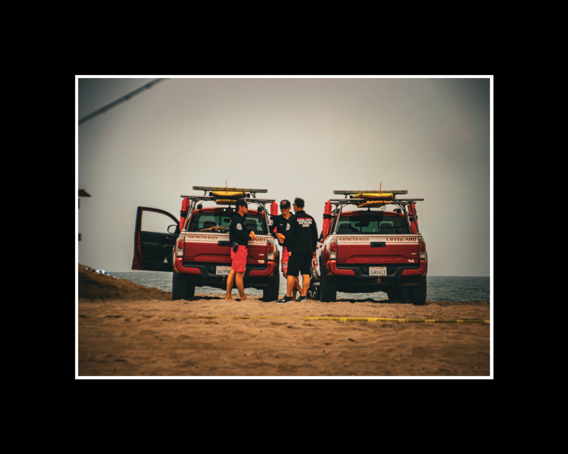 Photo of Huntington Beach lifeguards with jeeps on a cloudy day at the beach