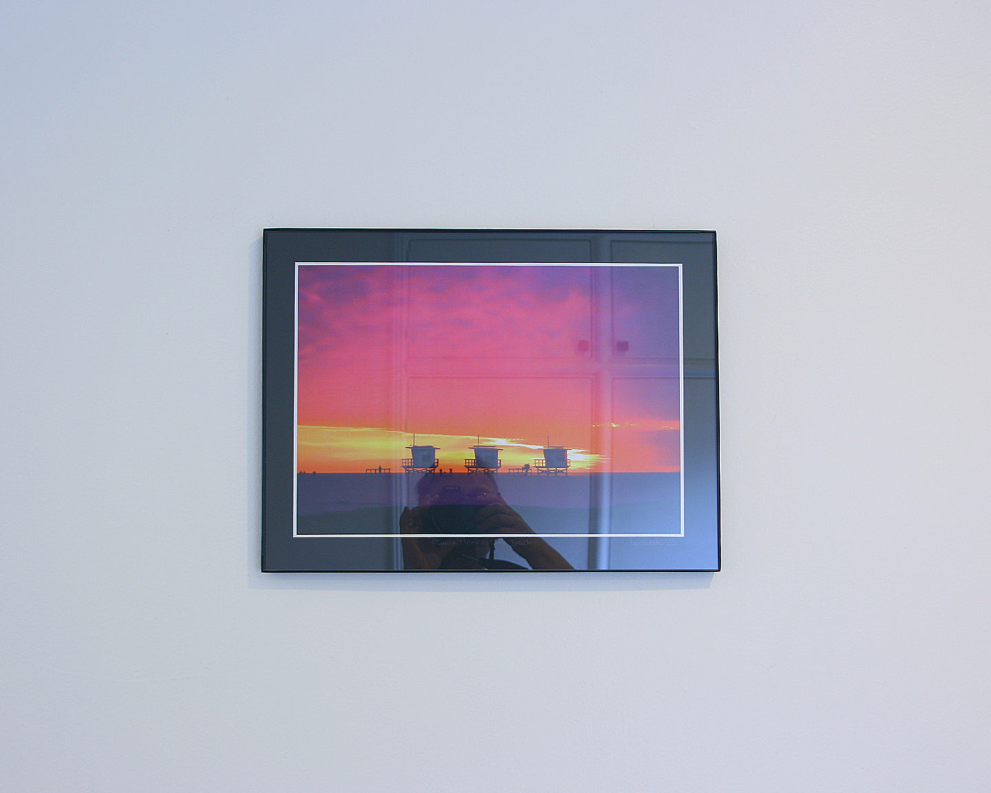 Three lifeguard towers on Santa Monica Beach under a pink and yellow winter sunset